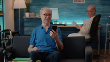 Yaşlı adam online konferans görüşmesini akıllı telefondan kullanıyor.