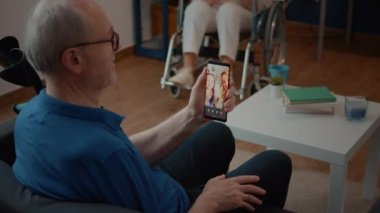 Video görüşmesine katılmak için cep telefonu tutan yaşlı kişi