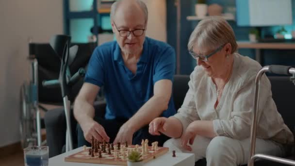 Äldste par med funktionshinder spelar schackspel ombord hemma — Stockvideo