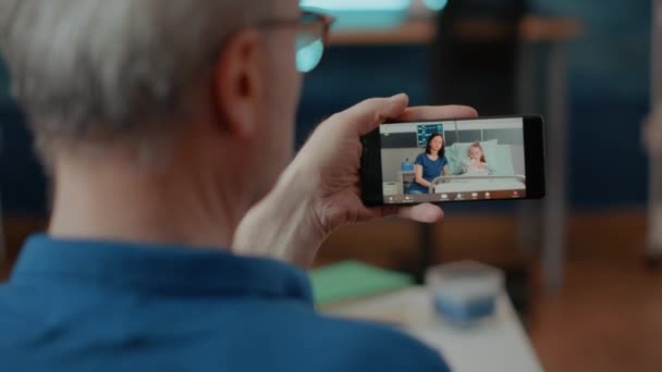 Adulto jubilado usando videollamada en línea en teléfono móvil — Vídeo de stock
