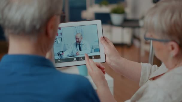 Idosos conversando com o médico em teleconferência — Vídeo de Stock