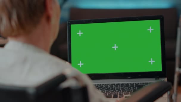 Oudere persoon met een handicap met behulp van groen scherm op laptop — Stockvideo