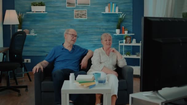 Пенсионеры смотрят комедийный фильм дома по телевизору — стоковое видео