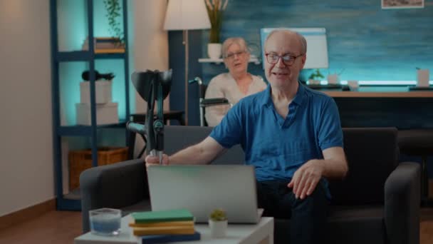 Senior man genieten van online video bellen op laptop met familie — Stockvideo