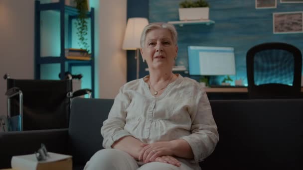 Portræt af senior kvinde med fysisk skade sidder på sofaen – Stock-video