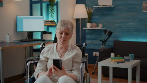 Starszy dorosły z niepełnosprawnością przeglądający internet na smartfonie — Wideo stockowe