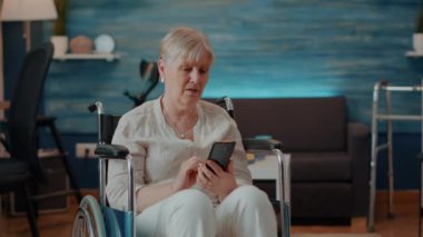 Tekerlekli sandalyede oturan ve akıllı telefon kullanan son sınıf öğrencisi.