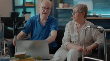 Yürüyen iskelet ve koltuk değnekleriyle dizüstü bilgisayar kullanan yaşlı insanlar.