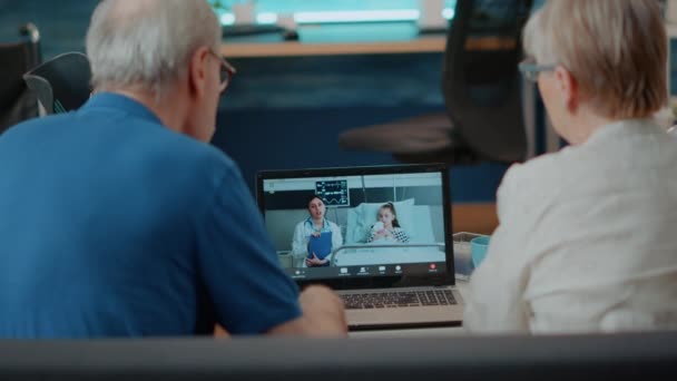 Бабушка и дедушка разговаривают с врачом и ребенком в больнице на видео-звонок — стоковое видео