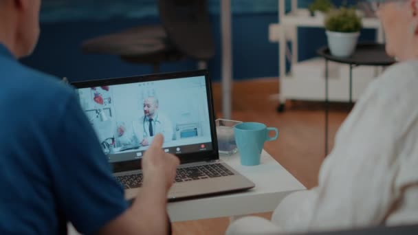 Pareja jubilada haciendo consulta en línea en videollamada con médico — Vídeos de Stock
