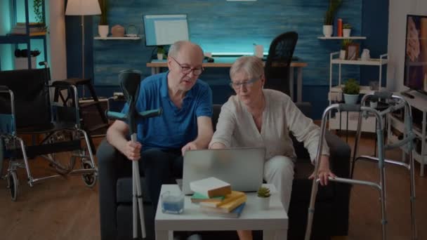 Oudere paar met chronische handicap met behulp van laptop samen — Stockvideo