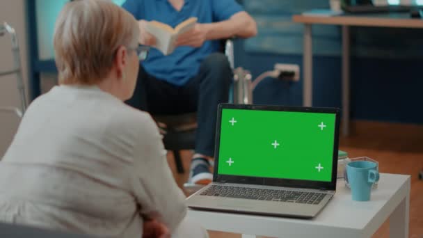 Старуха с инвалидностью анализирует зеленый экран на компьютере — стоковое видео