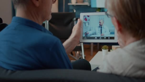 У віці чоловік і жінка використовують онлайн відеодзвінок, щоб поговорити з лікарем — стокове відео