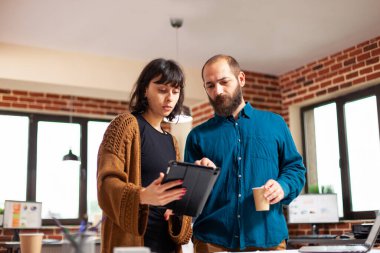 Tablet bilgisayarlı kadın yönetici şirket raporunu girişimciye gösteriyor