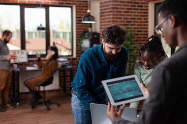 Çok ırklı iş adamları ellerinde pazarlama cirosuyla tablet bilgisayar tutuyorlar.