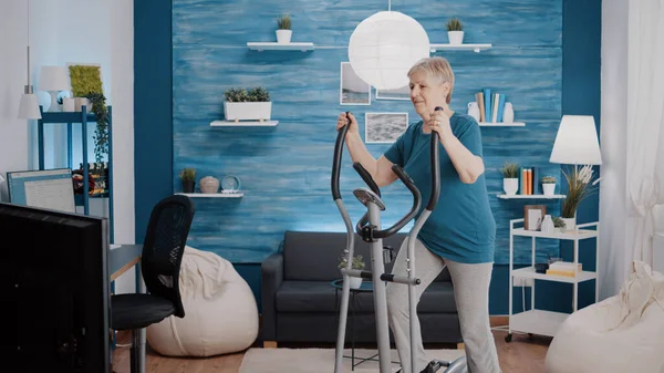 Pensionné faisant de l'exercice physique avec une machine cardio — Photo