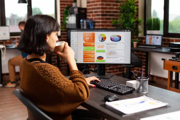 Empresária segurando xícara de café analisando gráficos financeiros digitando estratégia de marketing — Fotografia de Stock