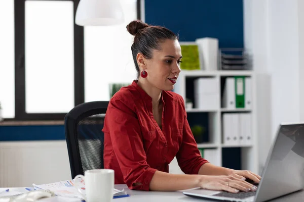 Впевнена бізнес-леді в червоній сорочці працює за столом в стартап-офісі . — стокове фото
