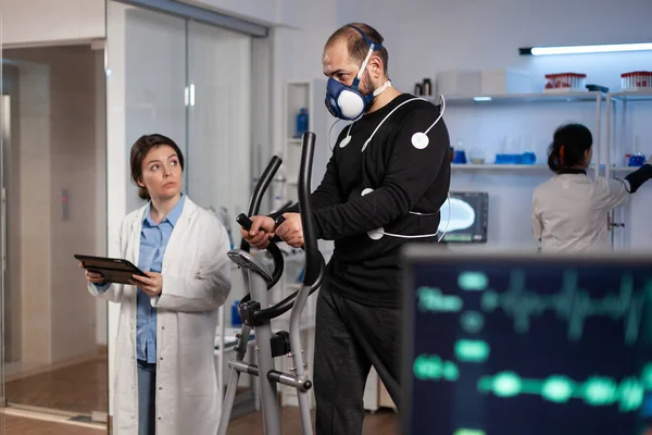 Athlète homme avec des électrodes médicales sur elle fonctionnant sur le vélo de fitness travaillant à l'endurance du corps — Photo