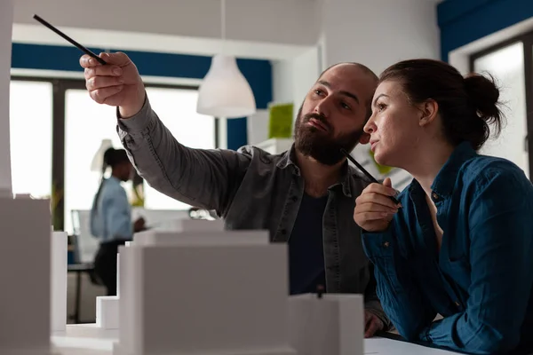 Architectural designers team pointing pen at skyscraper discussing architecture design — Stock Photo, Image