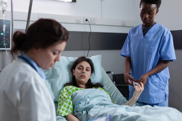 Krankenschwester misst spo2 Sättigung mit Pulsoximeter am Finger des Patienten, während Arzt Laborergebnisse liest — Stockfoto