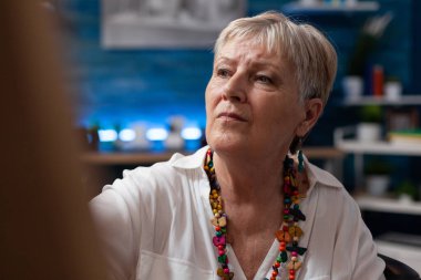 Renkli kolye takan gri saçlı yaşlı kadının portresi.