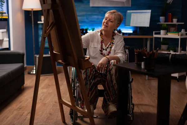 坐在轮椅上，用铅笔在帆布上画黑白草图的老年妇女 — 图库照片