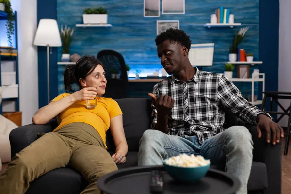 Alegre interracial casal sentado no sofá no sala de estar — Fotografia de Stock