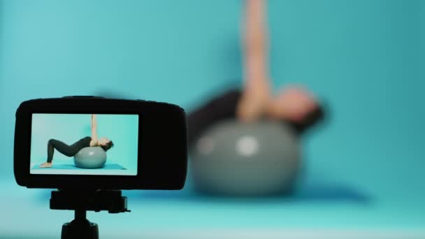 Formda bir kadın video kamerada dambıllarla fiziksel egzersiz yapıyor. — Stok video