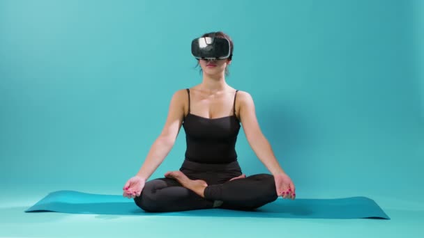 Yoga minderinde vr gözlüklü Lotus pozisyonunda oturan kadın. — Stok video