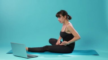 Formda bir kadın egzersiz yapıyor ve meditasyon videosu izliyor.