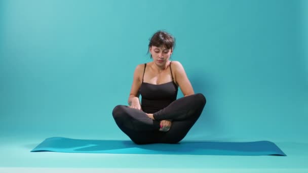 Fit mulher sentada em posição de lótus no tapete de ioga e respiração — Vídeo de Stock