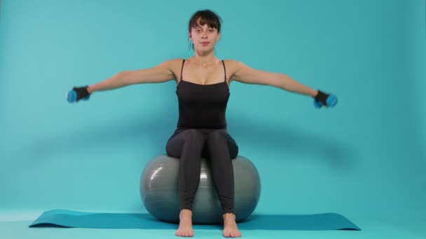 Atlet mengangkat dumbel dan duduk di atas bola kebugaran — Stok Video