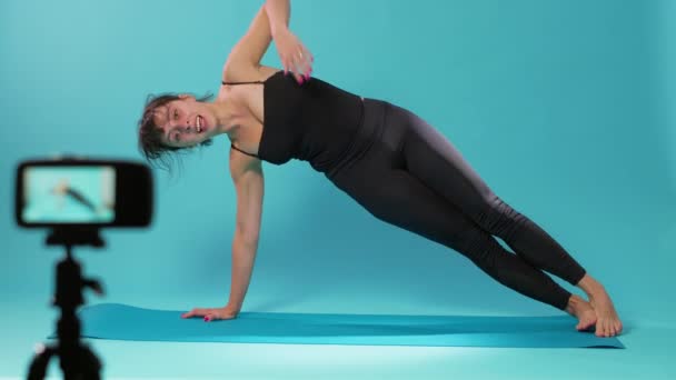Инструктор по йоге снимает упражнения на растяжку на камеру в студии — стоковое видео