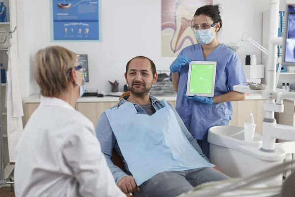 Стоматологическая бригада обсуждает с пациентом лечение зубов — стоковое фото
