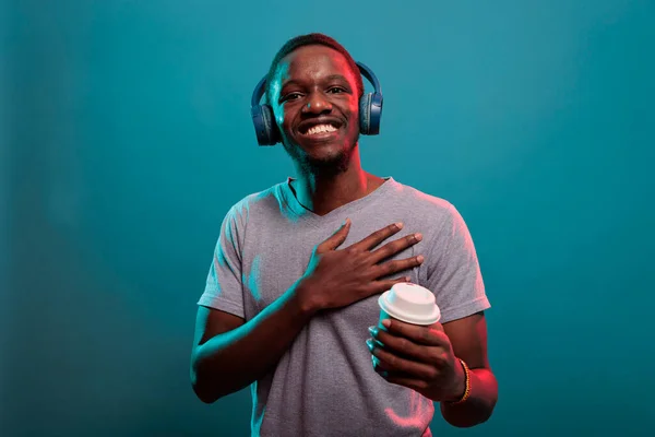 Vrolijke man met een kop koffie en genieten van muziek op de headset — Stockfoto
