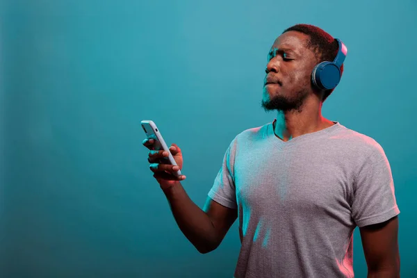 Millennial man using mobile phone and enjoying music on headphones — Stock Photo, Image