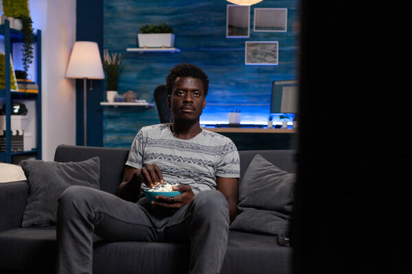 Relaxed young man resting on sofa watching soccer game on television