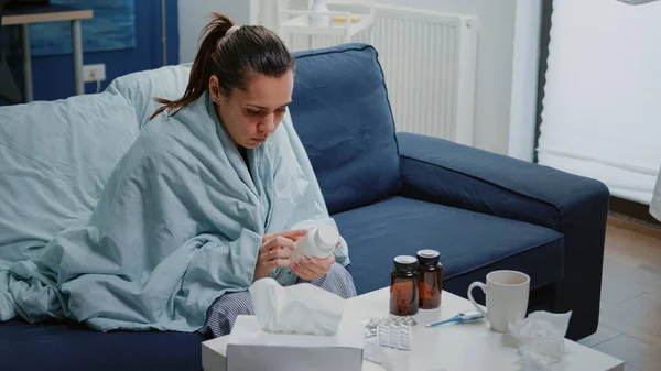 Nemocná žena čtení štítek na lahvičce pilulek a léků — Stock fotografie