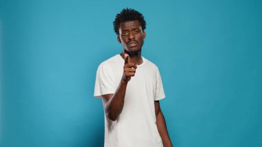 Afrikalı Amerikalı adam kamerayı parmaklarıyla işaret ediyor.