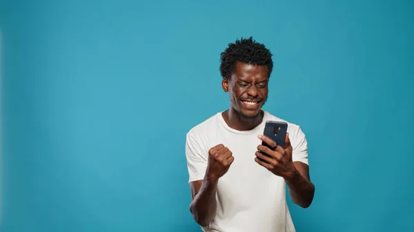 Africano americano homem sentindo animado e usando smartphone — Fotografia de Stock