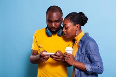 Erkek arkadaş ve kız arkadaş akıllı telefondan video izliyorlar.