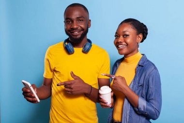 Erkek arkadaş ve kız arkadaş stüdyodaki akıllı telefon ekranını işaret ediyor.