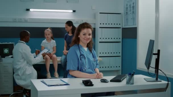 Portrét ošetřovatelky sedící za stolem v ordinaci lékaře — Stock video