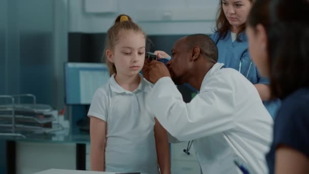 Лікар проводить отологічне обстеження з отоскопом, щоб побачити інфекцію вуха — стокове відео