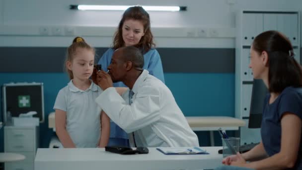 Médico que usa otoscopio en un niño pequeño para hacer un examen de oído — Vídeos de Stock