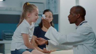 Doktor ısıyı ölçmek için çocuk üzerinde termometre kullanıyor.