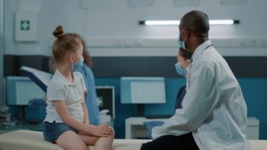 Doktor ve hemşire hasta çocuğa konsültasyonda bir şişe hap veriyor.