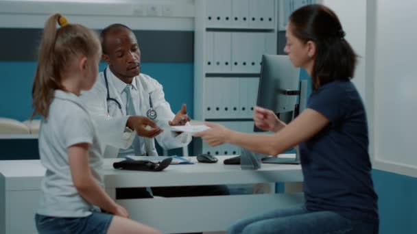 Physician giving prescription document for free medicine to parent — Stock Video