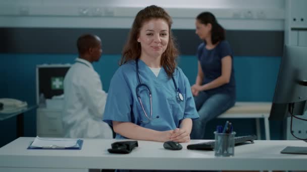 Портрет женщины-медсестры, улыбающейся и носящей униформу в офисе — стоковое видео